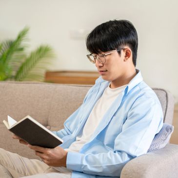 Young man reading a book on a cozy sofa.