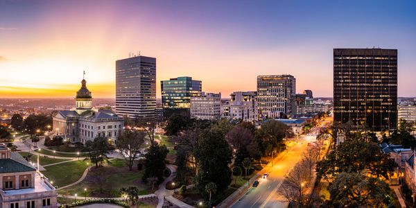 Columbia, South Carolina skyline at sunset with illuminated buildings and streets.