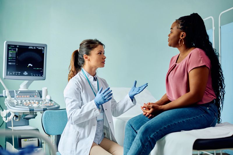 African American woman communicating with her doctor in medical examination room.