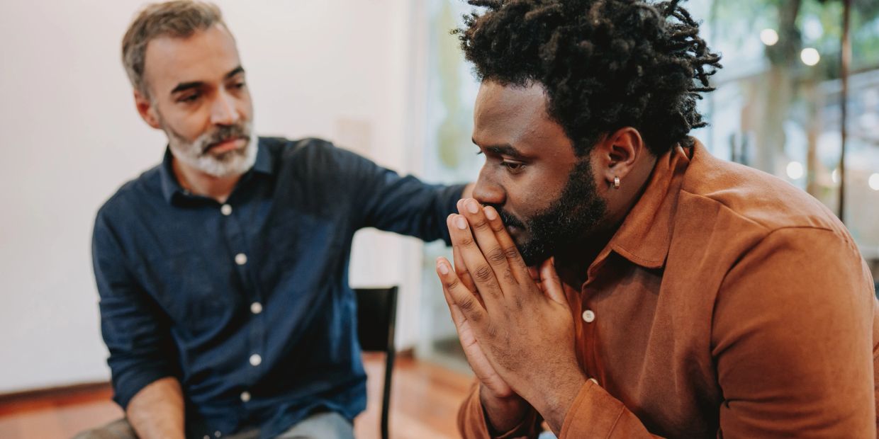 Man comforting another man who looks worried.