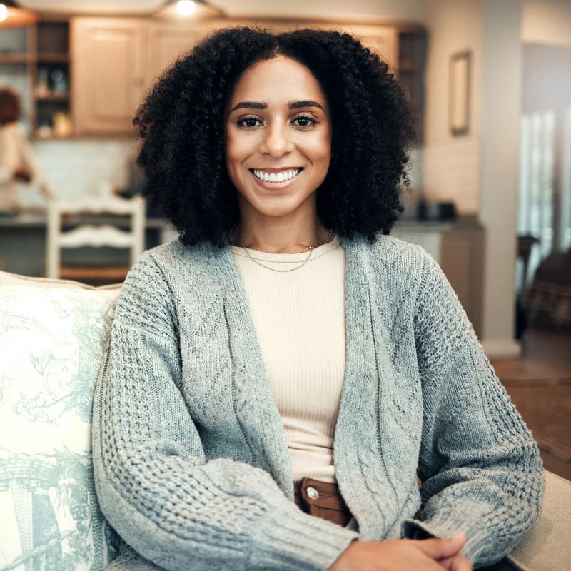 Happy, smile and portrait of black woman on sofa in living room for relax, break and satisfaction. Calm, happiness and free time with female sitting at home for positive, confident and carefree