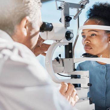 Woman undergoing eye examination with slit lamp at optometrist.