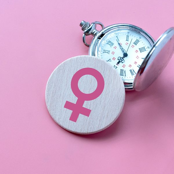 Pocket watch with female gender symbol on wooden disc.