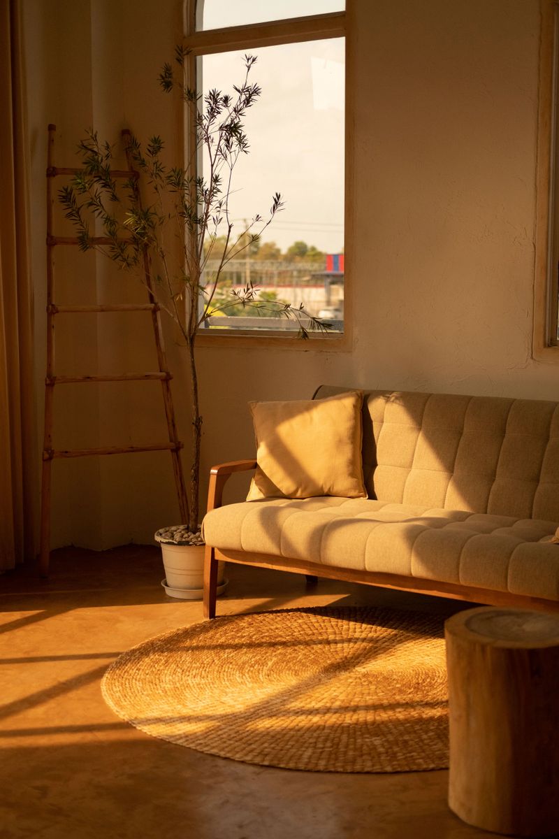 A modern white sofa situated in front of a large window in a living space, providing a bright and inviting atmosphere