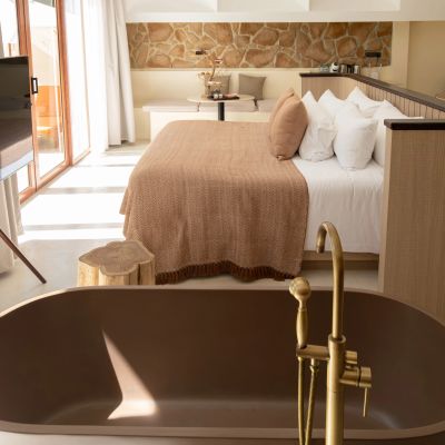Cozy bedroom with earthy tones and a stylish bathtub in the foreground.