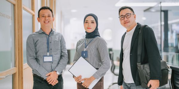 Three professionals posing in an office hallway.