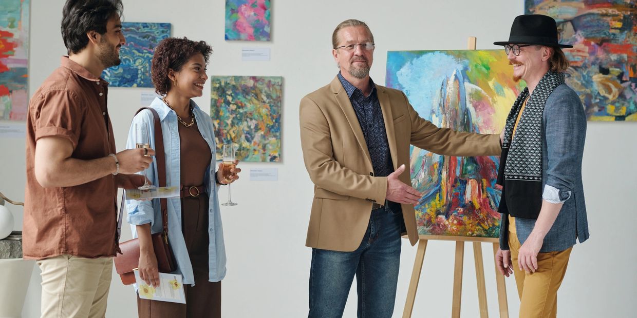 People enjoying an art gallery event with paintings and drinks.