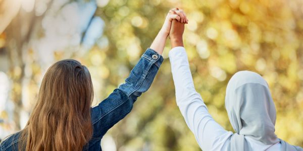 Two friends (converts and reverts) holding hands in support and unity outdoors.