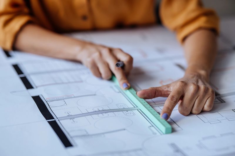 A close up view of an unrecognizable Caucasian architect drawing a blueprint.