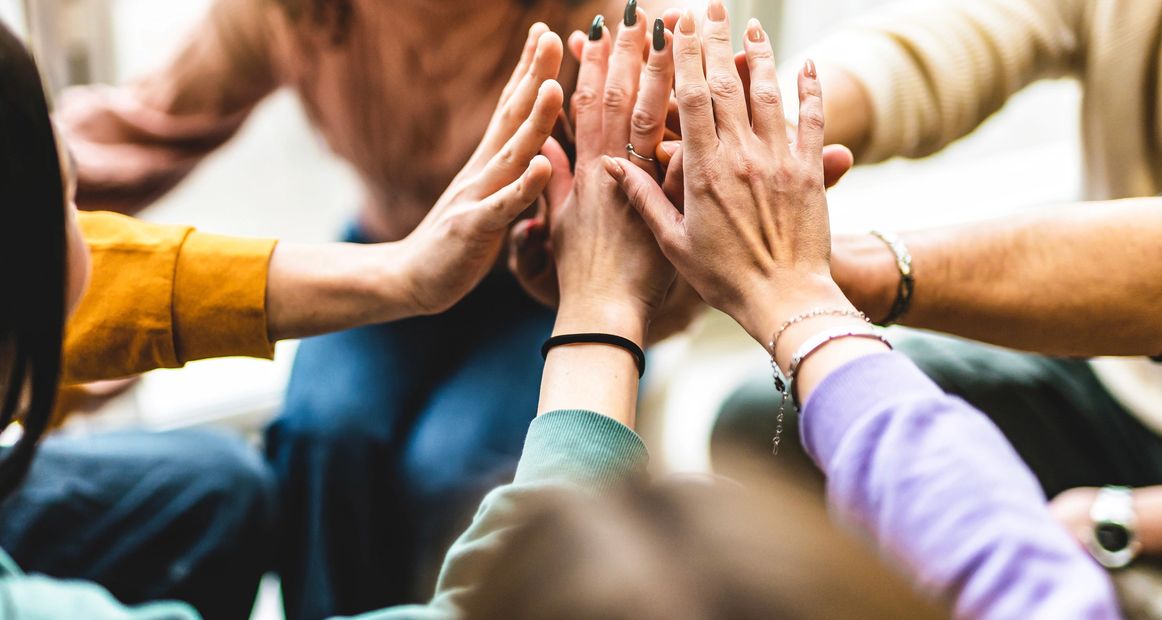 Group of people joining hands in a supportive gesture.