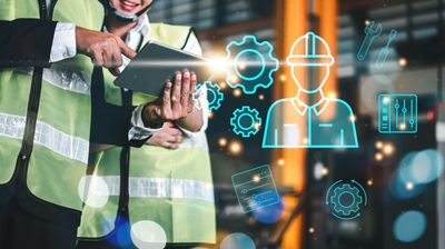 Engineers in safety vests using a tablet with digital engineering icons overlay.