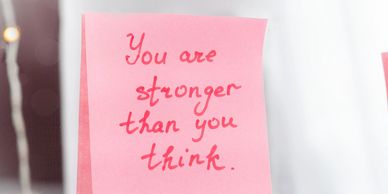 Sticky note with motivational message written in red ink.