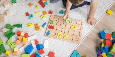 Toddler playing with alphabet puzzle and blocks.