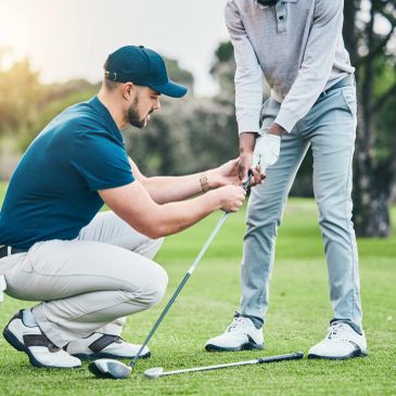 Golf instructor teaching grip to a player on a sunny course.