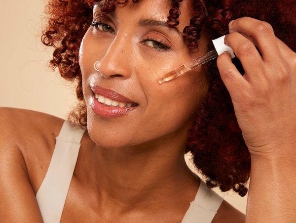 Woman applying facial serum with a dropper.
