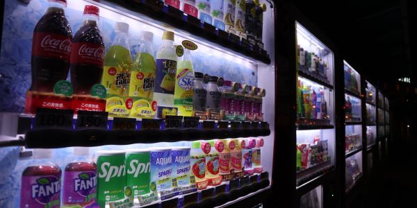 Row of illuminated beverage vending machines at night.