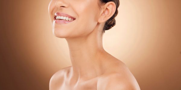 Close-up of a smiling woman with glowing skin and a natural makeup look.