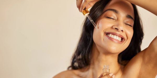 Woman happily applying facial serum.