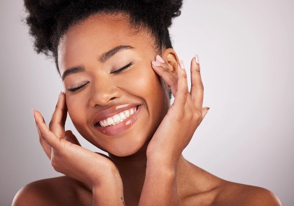 Smiling woman with eyes closed and hands near face.