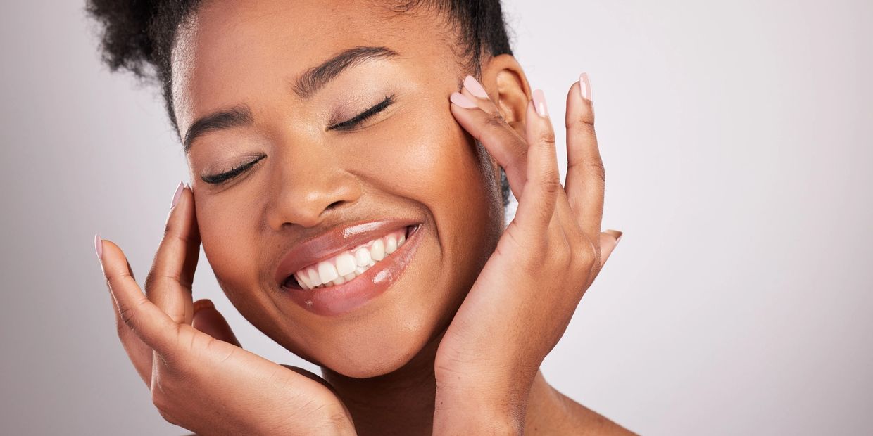 woman smiling and applying skincare