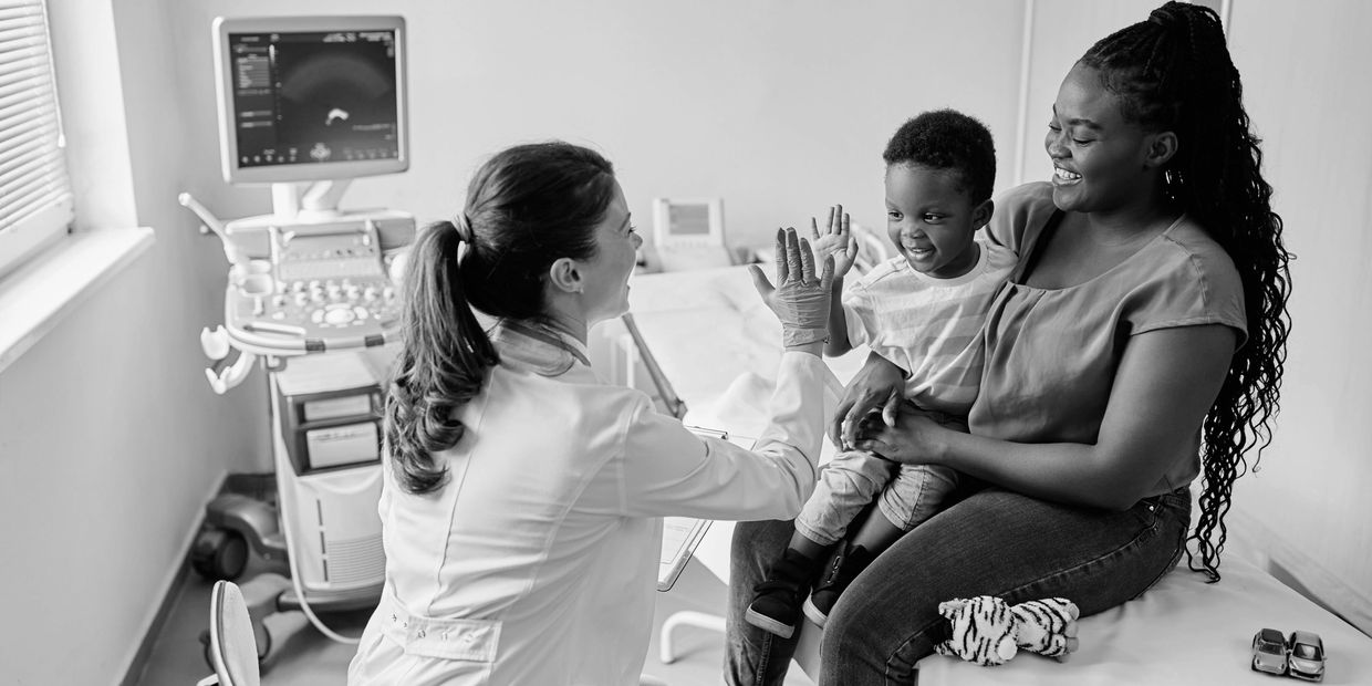 Doctor giving a high-five to a child while mother watches happily.