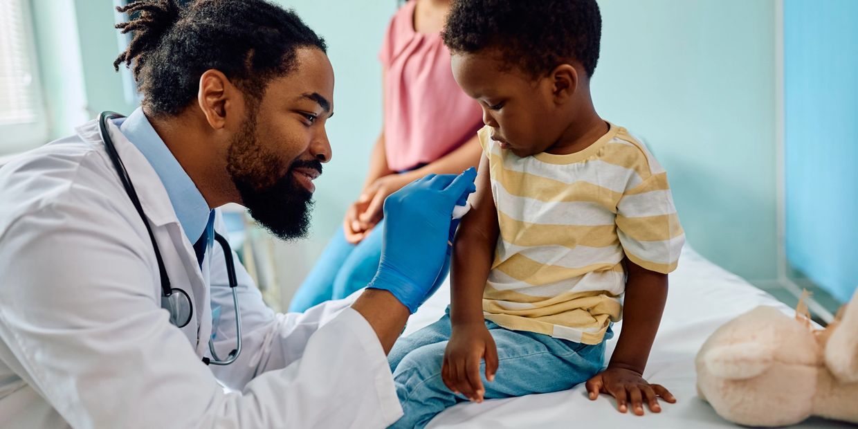 Doctor gently cleaning a young boy's arm before vaccination, with the mother smiling nearby. USB Angel Foundation volunteers serving the Atlanta community by providing emergency aid, health resources, and family recovery support. USB Angel Foundation- Angel Impact Center for local families in crisis. Atlanta, Georgia Nonprofit Near You - Tax deductible Donation