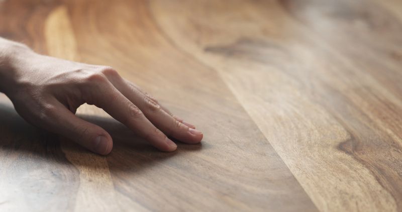 closeup of man hand checking hard wood surface, wide photo