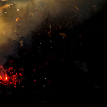 Crowd with lights and smoke at night, creating a dramatic atmosphere.