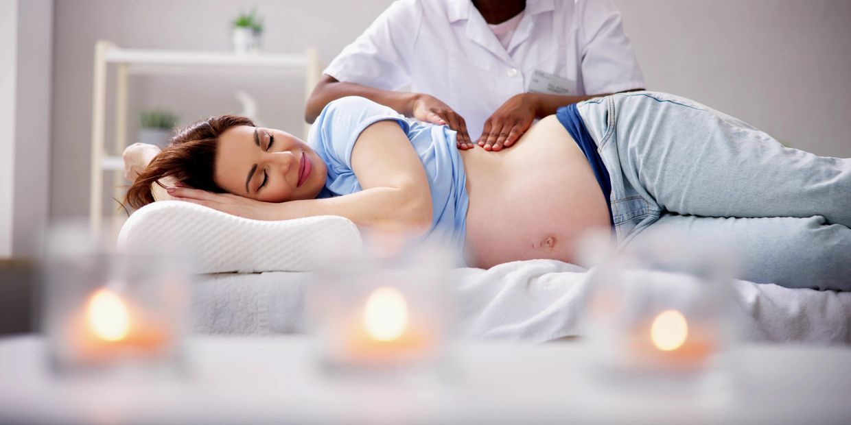 Pregnant woman happily receiving a gentle massage from a therapist.