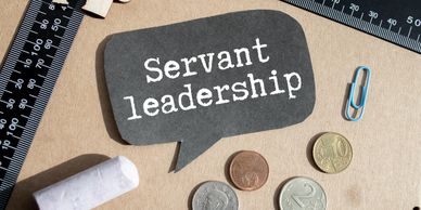 Speech bubble with 'Servant leadership' surrounded by rulers, coins, and paper clips.