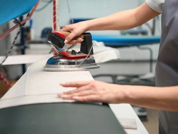 Person ironing fabric on a large ironing board in a workshop.