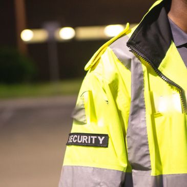 Close-up of a security guard wearing a high-visibility jacket at night.