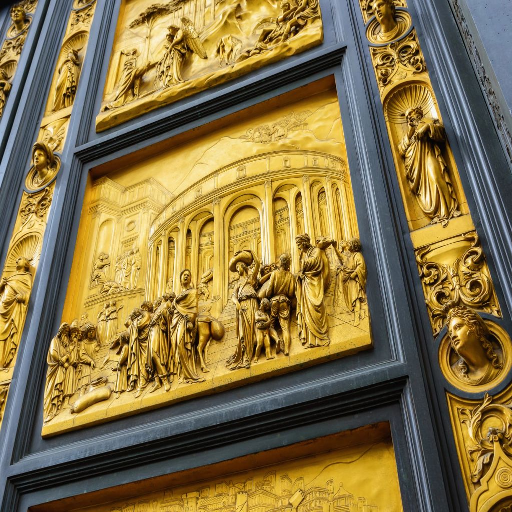 Ornate golden relief sculptures depicting historical scenes on a grand door.