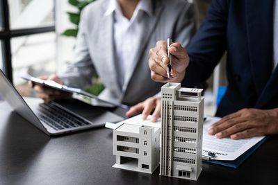 Two professionals discussing architectural models and documents.