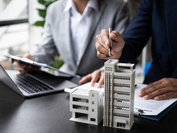 Two professionals discussing architectural models at a desk.
