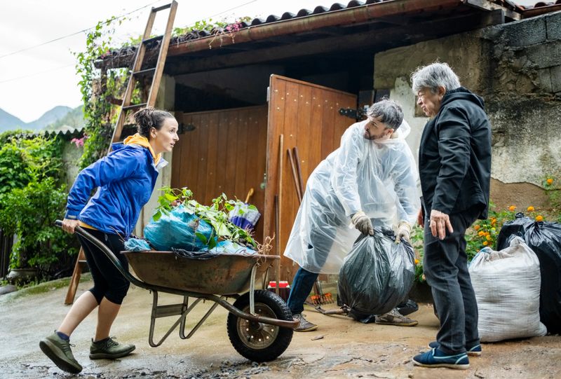 Group of male and female volunteers cleaning up the garbage and moving bags of trash on wheelbarrow from the roadside area during a community cleanup day