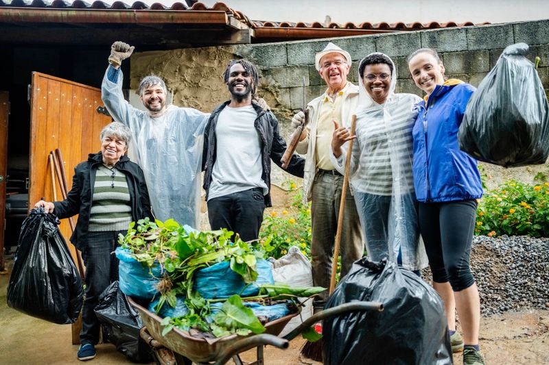 Portrait of a smiling group of diverse volunteers collecting litter together in their community during a cleanup day