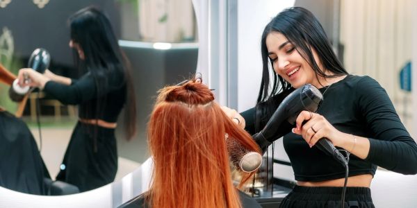 Hairdresser drying a client's hair with a blow dryer.