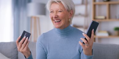 Happy elderly woman holding a phone and credit card.