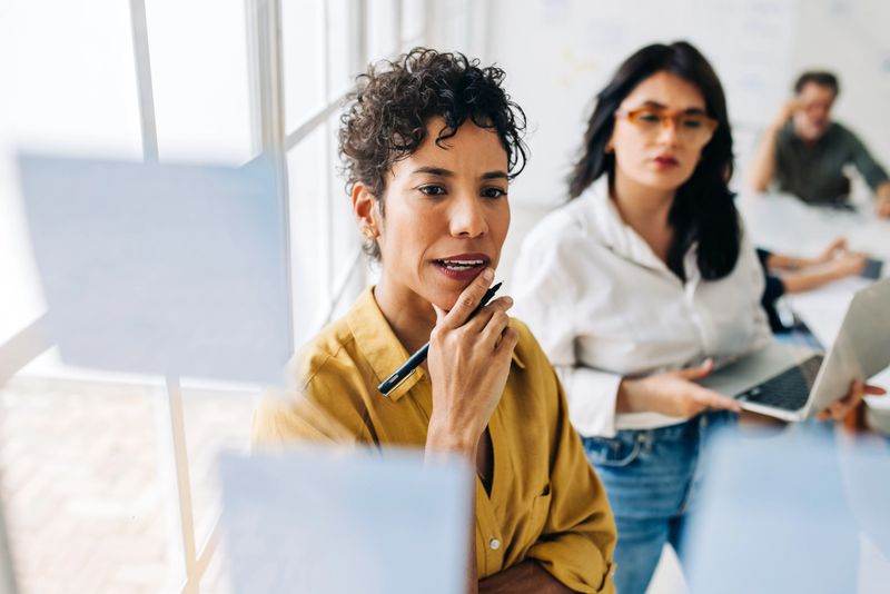 Business women brainstorming in a marketing agency. Creative business women writing ideas on sticky notes in an office. Female professionals working as a team.