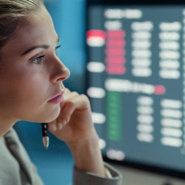 A woman intently studies stock market data on a screen.