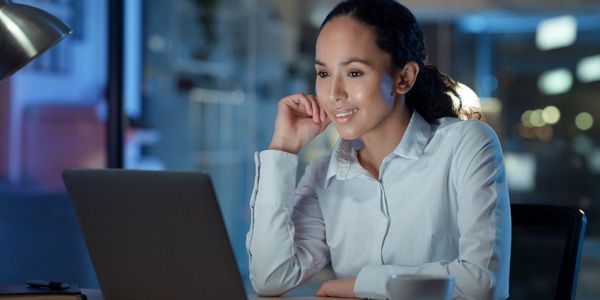 A woman working late on her laptop with a smile.