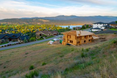 A house under construction on a hillside overlooking a lake and nearby homes.