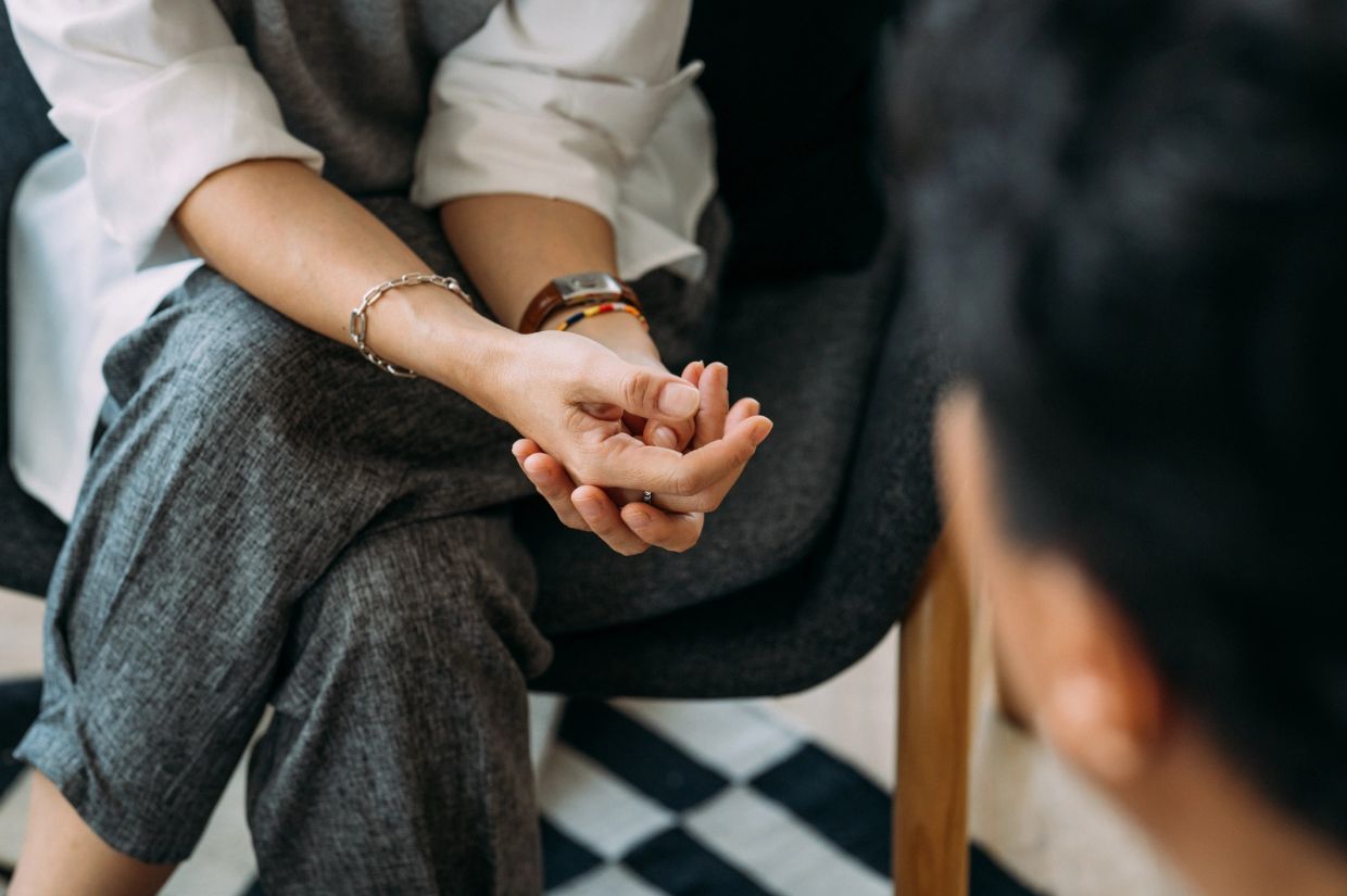 Two people engaged in a serious conversation, focusing on hands and body language.