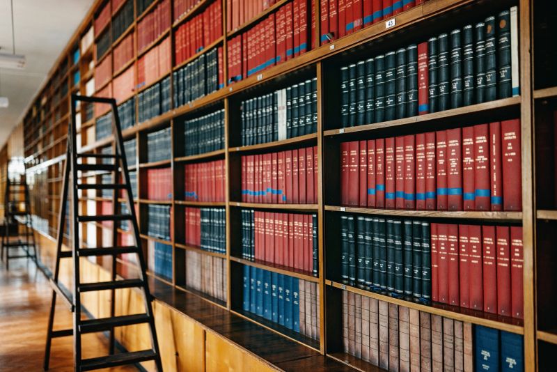 Photo of the university library  with  wooden desk chairs in the middle part of the room