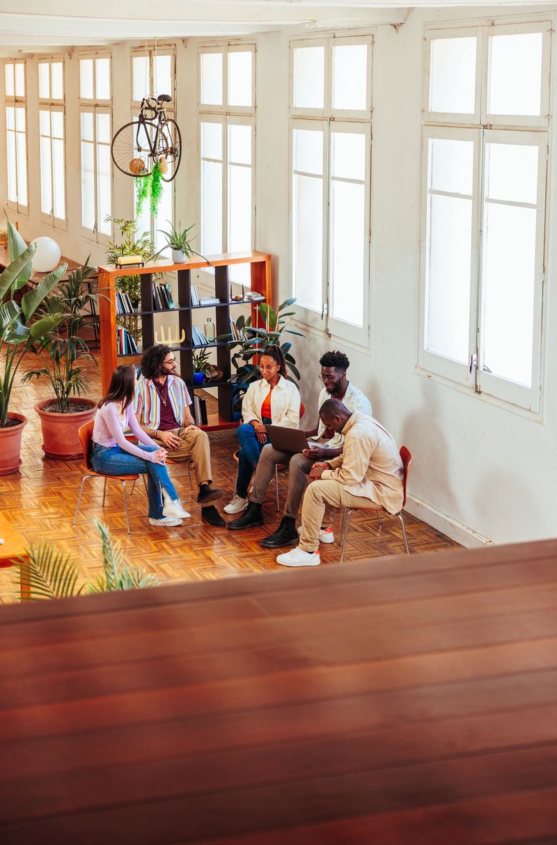 Four multiracial young people and Caucasian therapist talking during a group therapy session.
