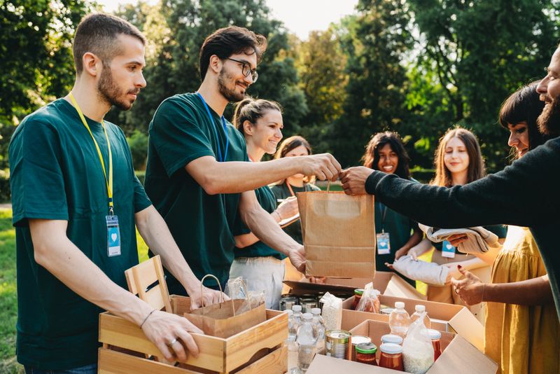 A couple is taking a bag of food at the food and clothes bank. Volunteers are working together at the humanitarian aid project.