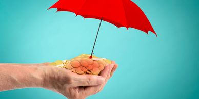 Hands holding coins protected by a red umbrella against a blue background.