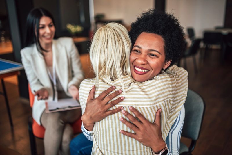 Support group patients hug each other during the therapy session. Group therapy session, addiction treatment or team building.