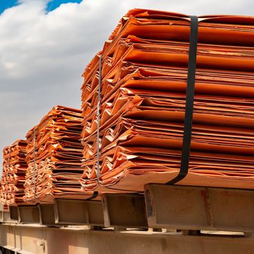 Stacks of orange folded metal sheets secured with black straps.